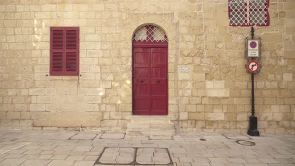 Big Closed Red Wooden Doors with Closed Window Shutters in Mdina