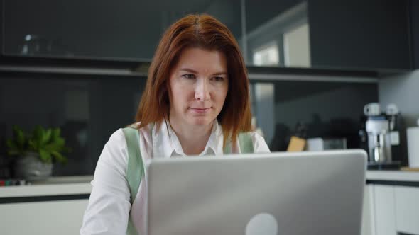 Businesswoman Working Remotely From Kitchen Using Laptop alt