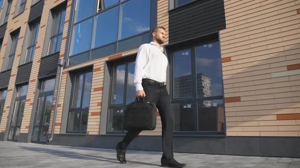 Successful Businessman with Briefcase Walking Near Modern Office Building alt