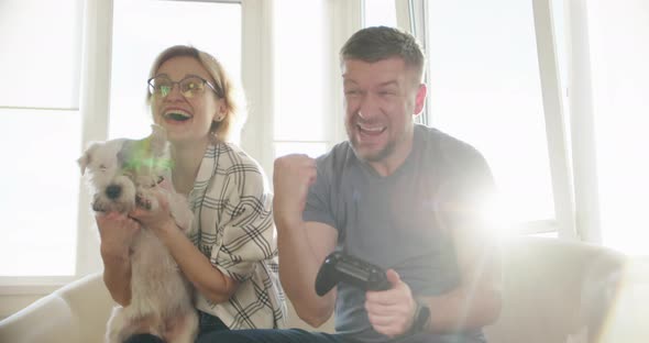 Happy Couple Sitting on the Sofa and Playing Video Games Using Controllers in Love Have Fun Playing alt