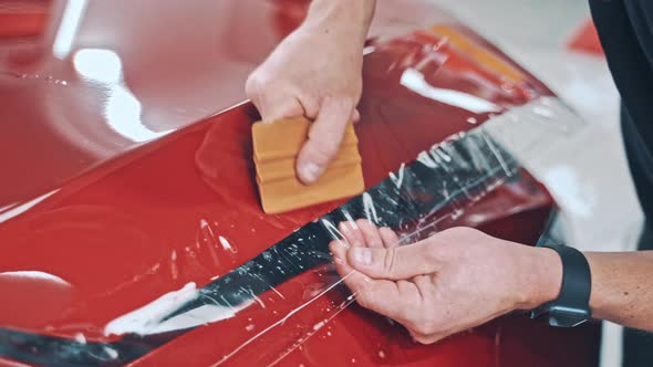 Professional Applying Protective Film to the Red Car alt