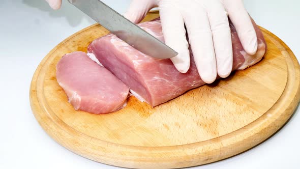 The cook cuts a fresh piece of pork on a wooden cutting board. Meat steaks for barbecue. BBQ food