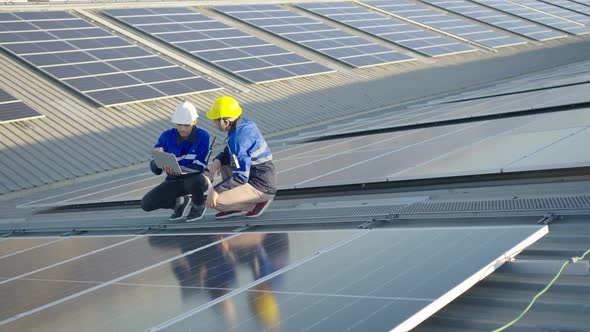 Asian technician inspection solar cell panels field of on roof top factory.