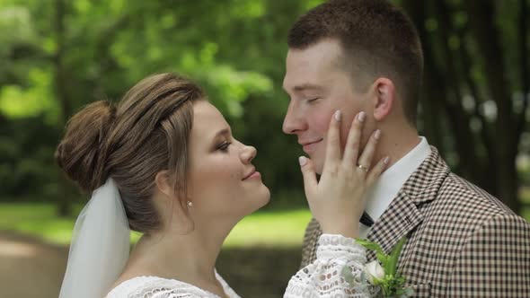 Newlyweds. Caucasian Groom with Bride Making a Kiss in Park. Wedding Couple. Man and Woman in Love alt
