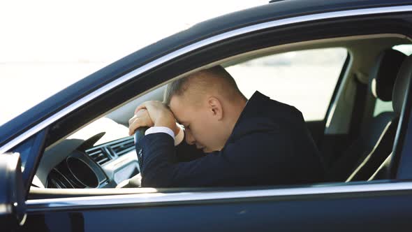 Business Man Leaning Her Head on Steering Wheel While Feeling Tired After Long Distance Riding