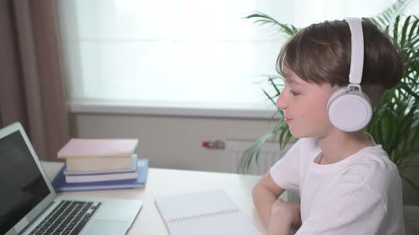 The Boy Listens Attentively To the Lecture in White Headphones