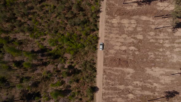 Car Drives on Gravel Road Between Green Forest and Dry Desert Land alt