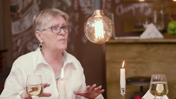 Old Lady on a Date Chatting with Her Partner Over a Glass of Wine alt