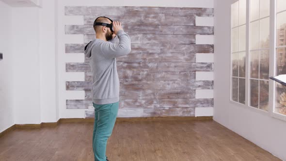Caucasian Man Using Virtual Reality Headest in Empty Apartment alt