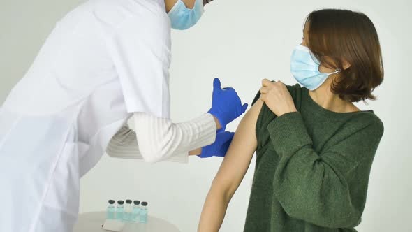 Female Doctor or Nurse is Giving a Shot or Vaccine to a Patient's Shoulder of Young Woman in Green alt