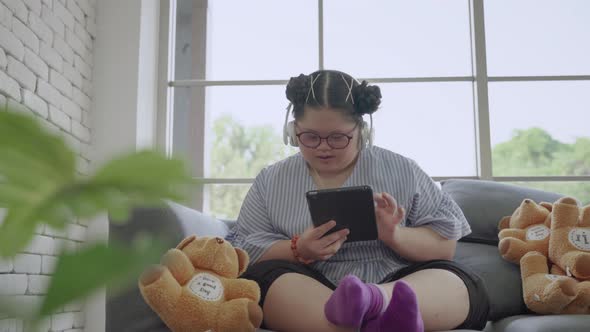 young Asian girl with Down's syndrome is playing a tablet alone in the room