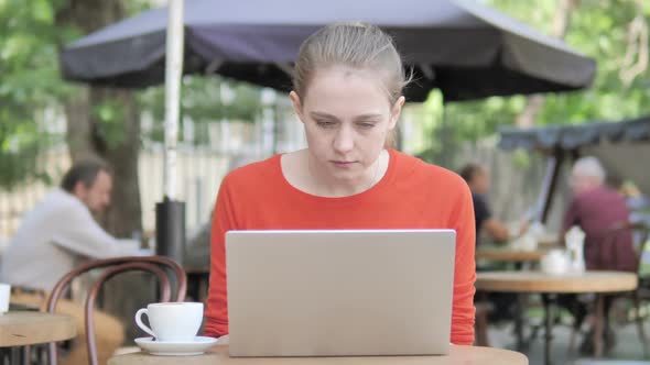 Young Woman Frustrated By Failure Sitting in Cafe Terrace alt