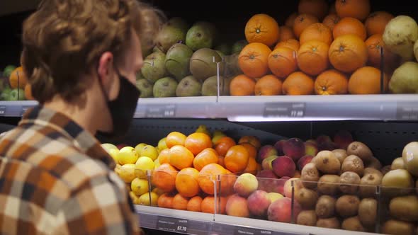Young Man in Plaid Shirt Wearing Respirator Tissue Black Mask Shopping for Fruits with Plastic Bag alt