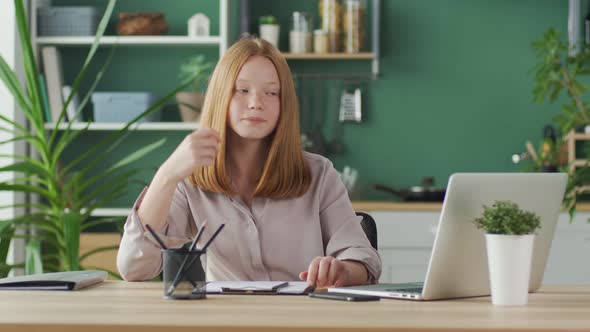 Tired Teenage Schoolgirl While Studying Online at a Laptop alt