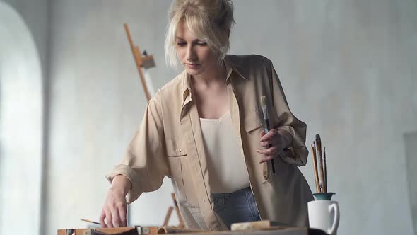 Woman Taking Painting Brush and Painting Tools from The Table