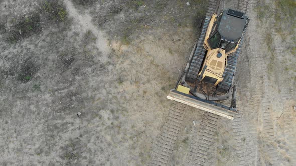 Top Aerial View on Tracked Bulldozer Rides on Sandy Road at Construction Site alt