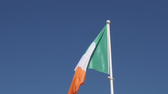 Tricolour striped shiny  Ireland flag against blue sky on wind 4K 2160p 30fps UltraHD footage - Oran