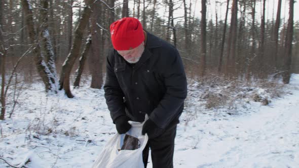 Senior Man with Grey Beard Fixes Large Bag with Firewood alt