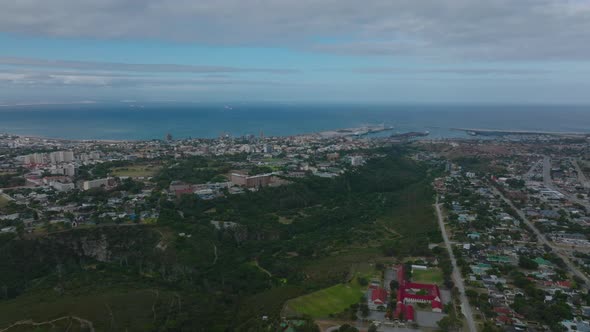 Aerial View of Green Valley with River Between Urban Neighbourhoods and Sea in Background alt