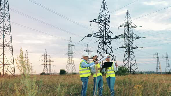 Energy Workers Are Discussing a Project Near Transmission Towers alt