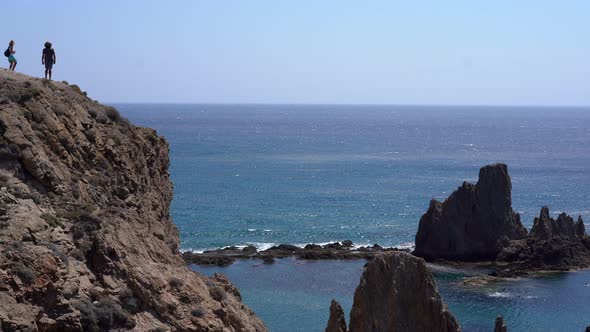 Couple on edge of cliff at Las Sirenas, Cabo De Gata, Almeria. Zoom in alt