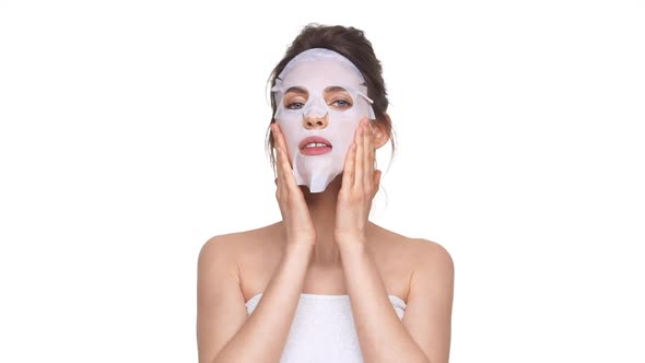 Young Caucasian Girl Applying Facial Mask Over White Background in Slowmotion alt