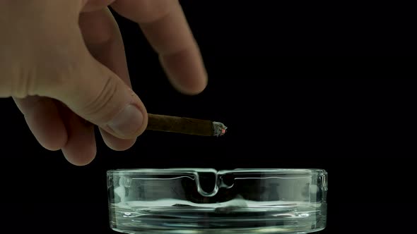 Shake Off Ashes Into An Ashtray On A Black Background, A Man Smokes A Cigar Close Up.