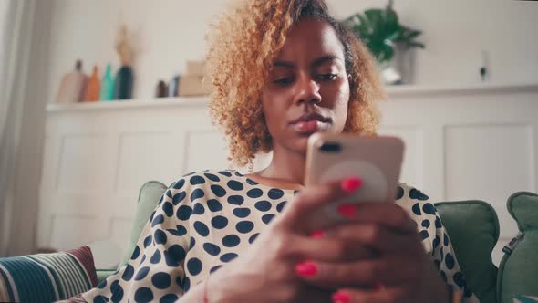 Focused Young African American Woman Carefully Typing Message on Mobile Phone alt