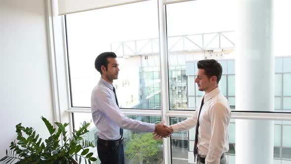 slow motion two young businessman indoor office interior shaking hands alt
