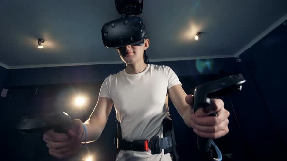 Equipped Teenage Guy Is Exploring Virtual Reality with the Help of a Simulator alt
