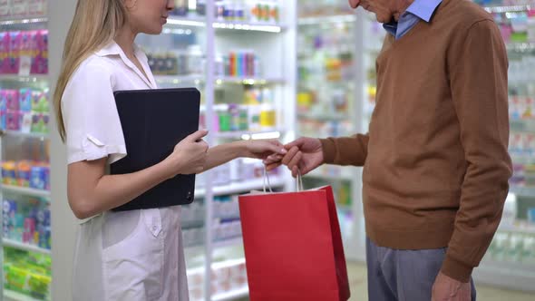 Side View Unrecognizable Pharmacist and Client Passing Shopping Bag Shaking Hands Standing in alt