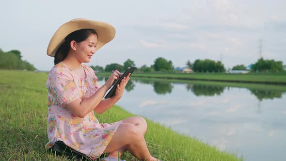 Adult woman sitting on the lawn using portable technology. Portable device tech usage concept. alt