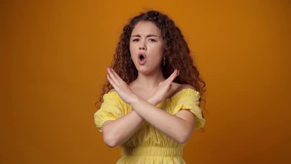 Curly Young Woman Showing 'Stop' Gesture Against Yellow Background
