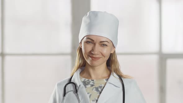 The lady doctor smiles and nods her head approvingly at the camera. Professional female doctor in un alt