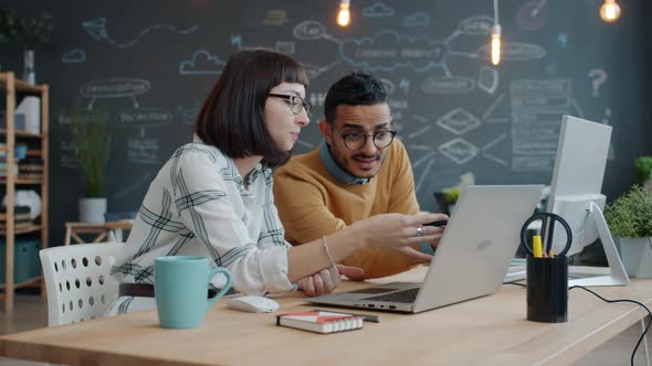 Mixed Race Business Team Man and Woman Talking in Office Looking at Laptop Screen alt