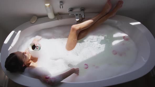 Woman drinking coffee while relaxing in a bathtub alt