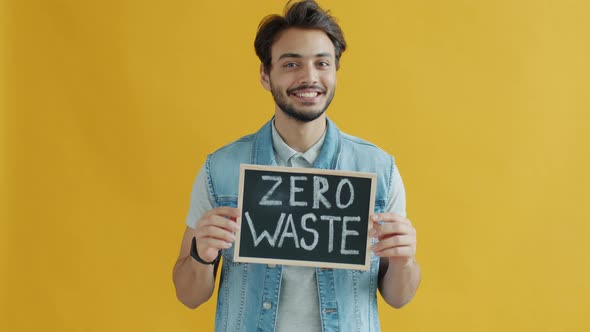 Slow Motion of Smiling Mixed Race Guy Holding Zero Waste Sign on Yellow Color Background alt