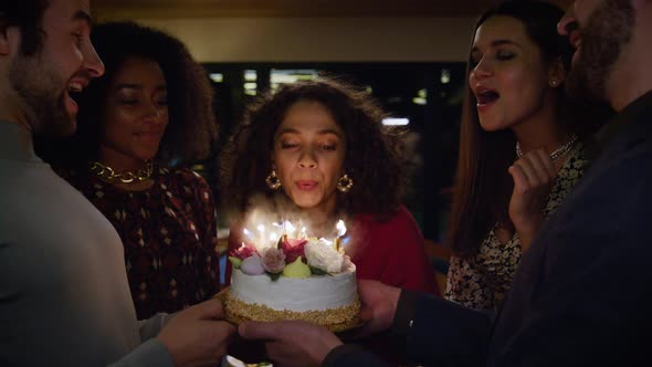 Happy Woman Blowing Candles on Birthday Cake at Friends Celebration Cafe Party alt