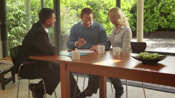 Wide shot off couple signing contract at dinning table and handshake sales person alt