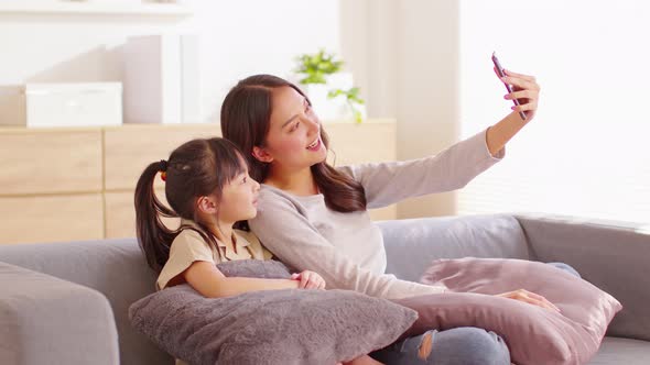 Asian young mother and her daughter have video call conference with family having fun together alt