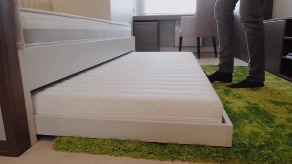 A Man Puts an Extra Bed in a Child's Bed.