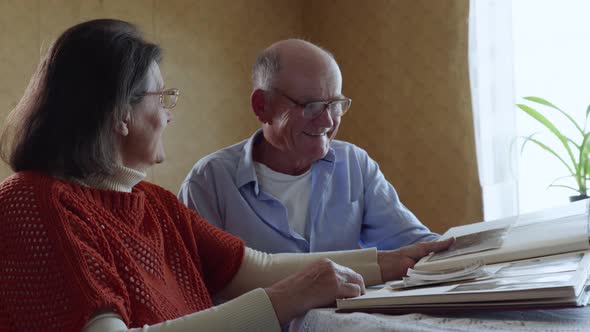 Elderly Couple in Love Enjoy Moments of Family Life Looking Through Old Photos From a Photo Album alt