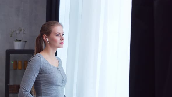 Young  girl is standing in front of the window alt