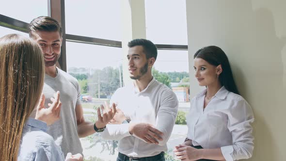 Light-flooded Room of Four Young People Two Young Women and Two Men Smiling Laughing and Talking To alt