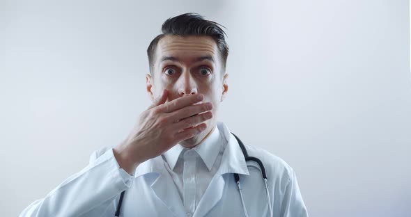 Shocked Man Doctor with Sudden News Closes From Fright Over White Background alt