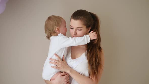 Mother in a White Coat Holds Her Little Blonde Daughter Against the Wall alt