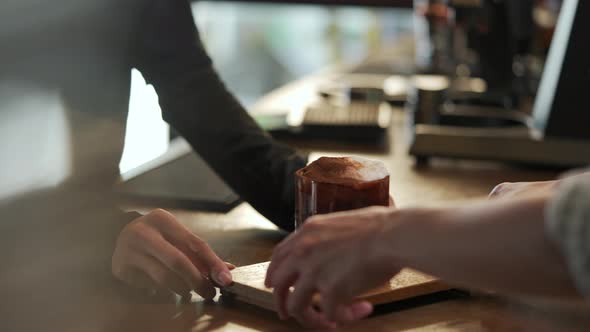 4K Asian woman barista serving iced chocolate with froth milk to customer alt