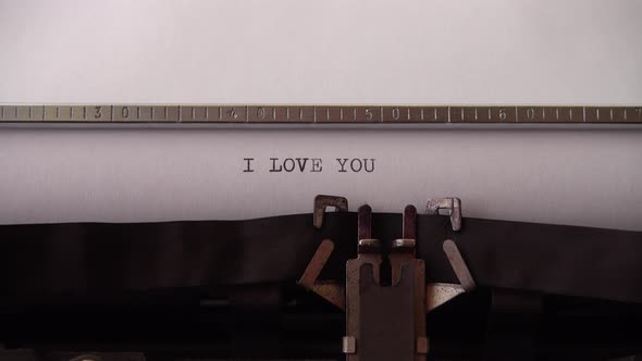 Typing phrase I LOVE YOU on retro typewriter. Close up. alt