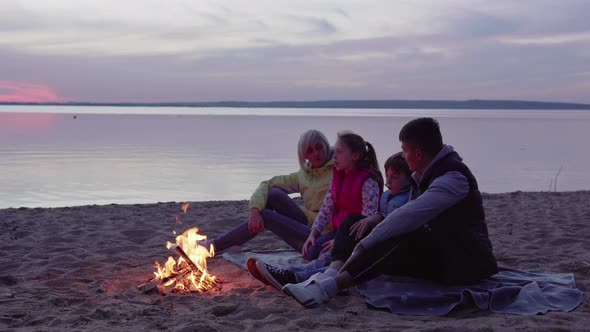 Family with Children Talking By Campfire at Sunset