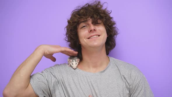 A Man with Curly Hair with a Pet Ratmouse on an Isolated Background in the Studio alt